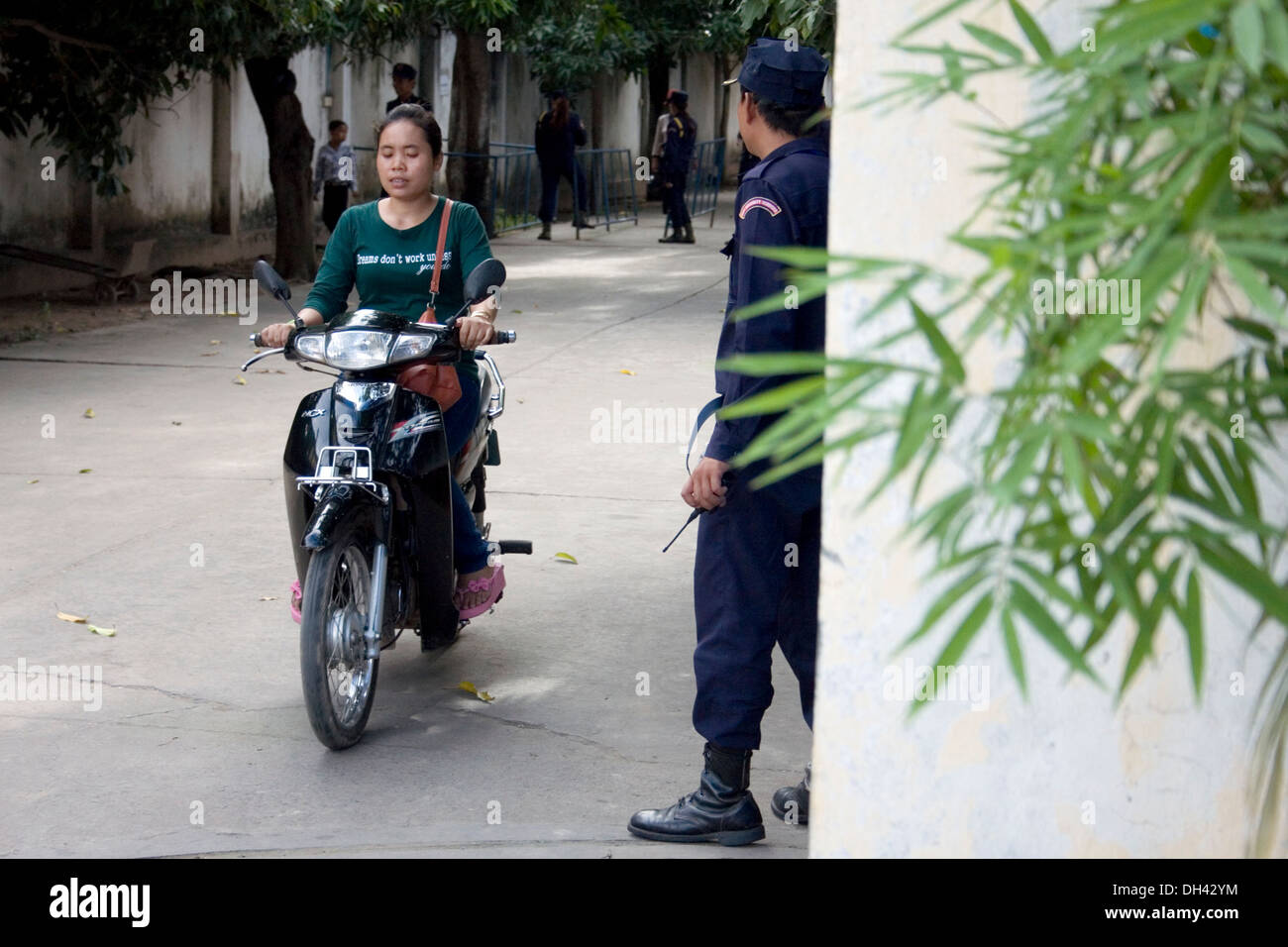 A women factory worker is leaving a garment factory on a Honda motorcycle after her shift in Phnom Penh, Cambodia. Stock Photo