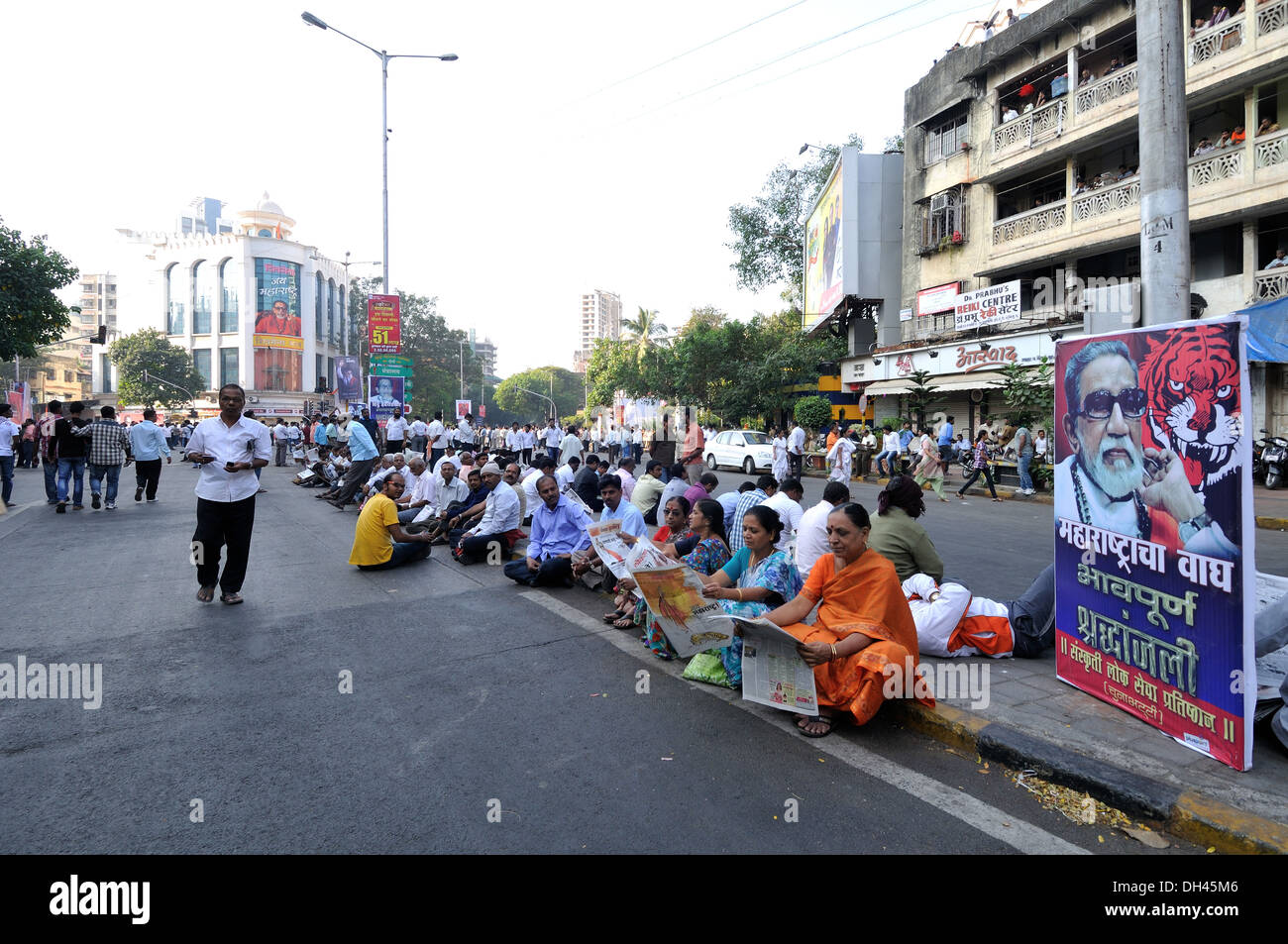 indian women reading newspaper reports about Balasaheb Thackeray Funeral Procession sitting on road divider at dadar mumbai maharashtra india November 2012 Stock Photo
