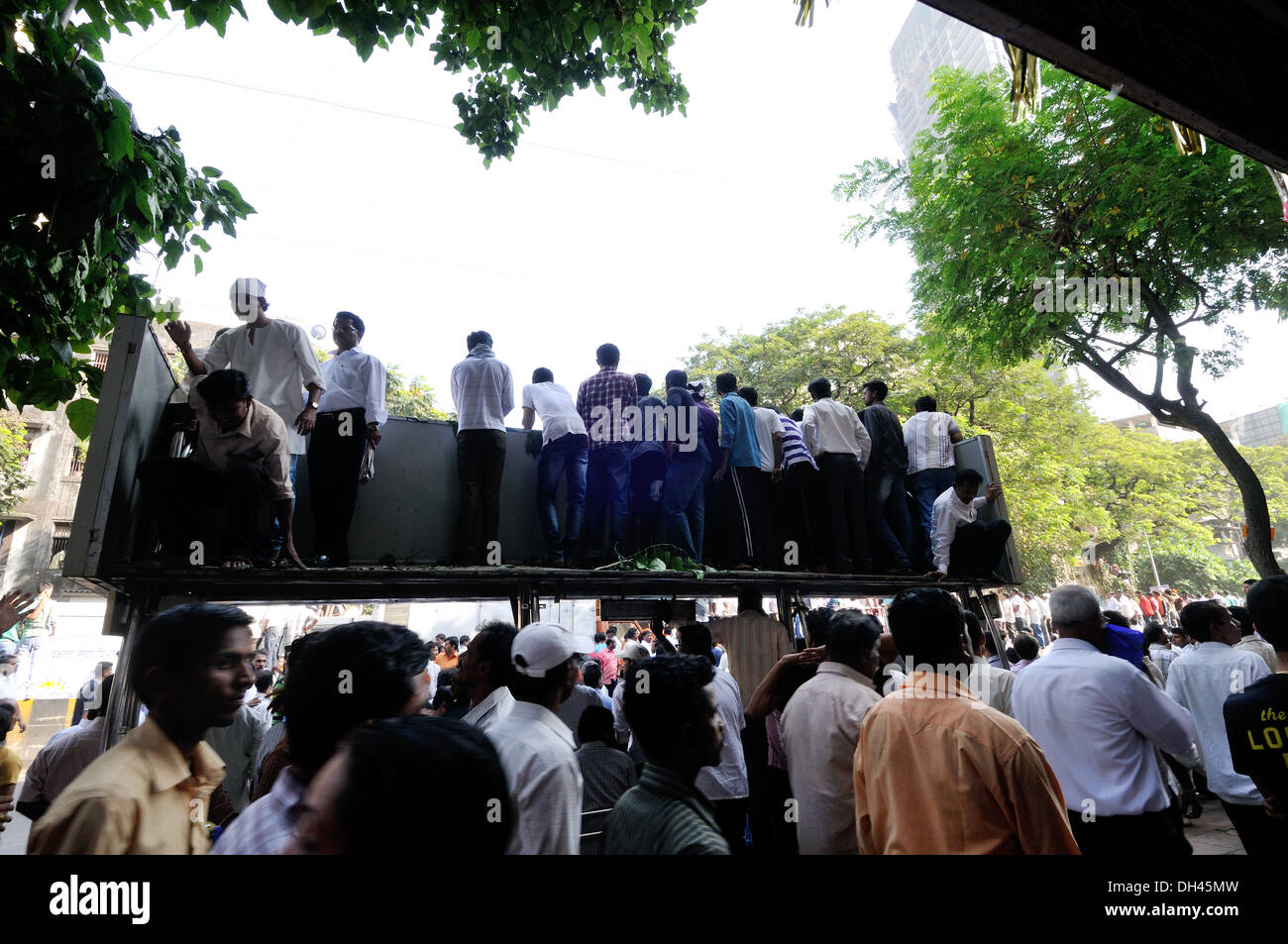 crowd of people standing on bus stop shelter roof to see Balasaheb Thackeray Funeral Procession dadar mumbai maharashtra india November 2012 Stock Photo