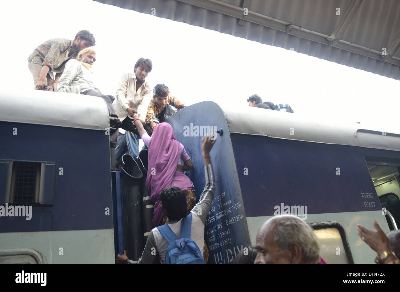 Indian man pulling up and woman climbing on the roof of train bogie compartment Jodhpur Rajasthan India Asia Stock Photo