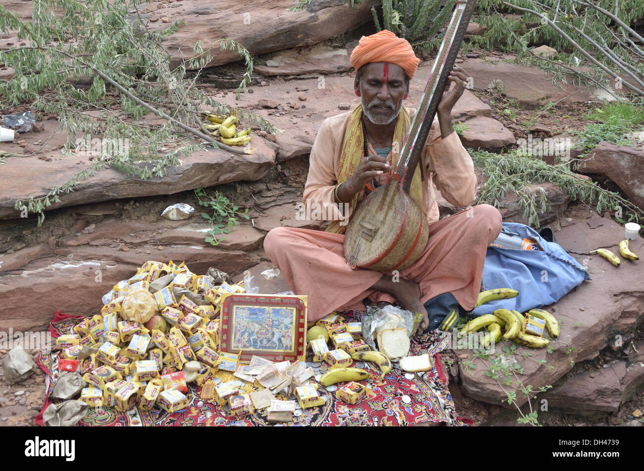 Beggar Sadhu playing string musical instrument Tambura on road side Jodhpur Rajasthan India Asia Stock Photo