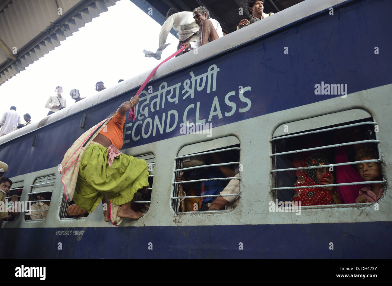 man pulling woman on the roof of train second class compartment bogie at Jodhpur Rajasthan India Asia Stock Photo