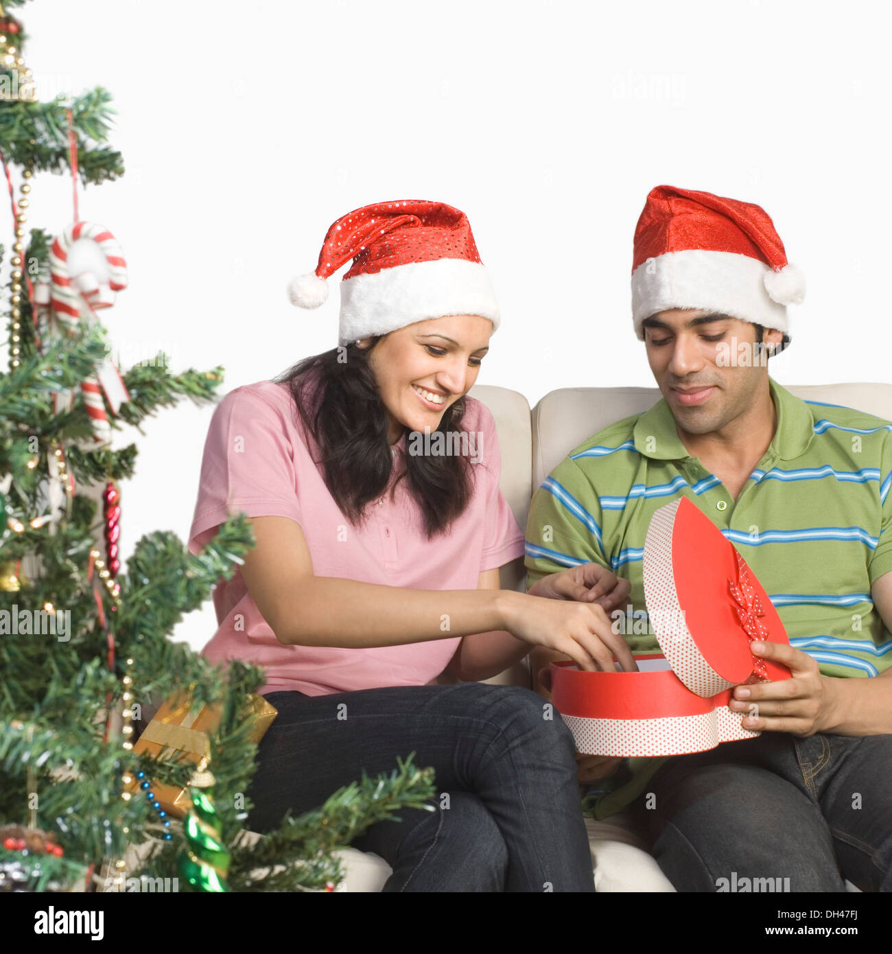 Couple sitting on a couch and unpacking a Christmas present Stock Photo