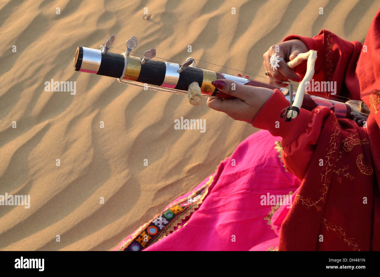 Woman playing one string Indian folk musical instrument Ravanhatta in desert Rajasthan India