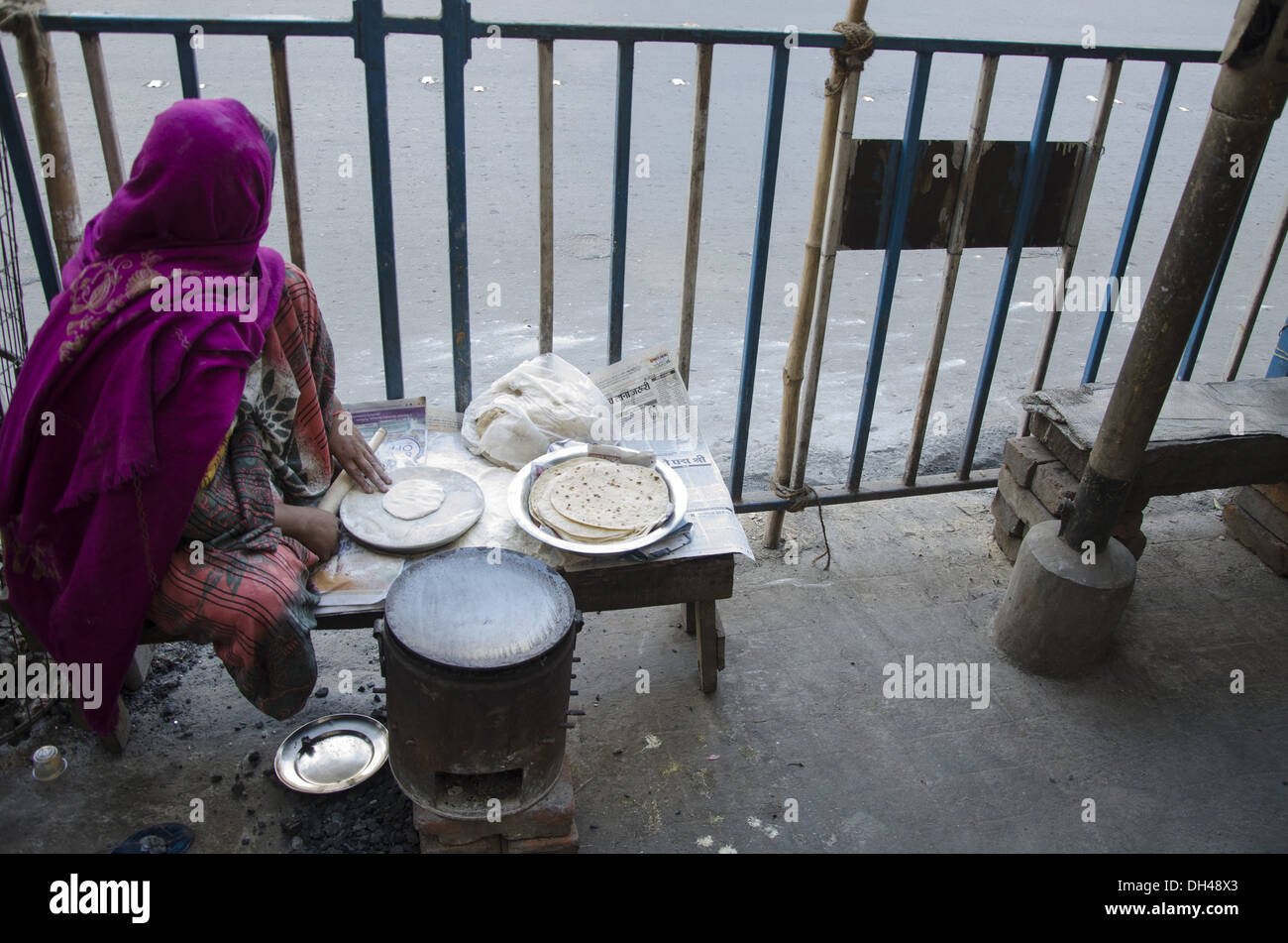 woman cooking preparing making roti bread footpath pavement kolkata West Bengal India Stock