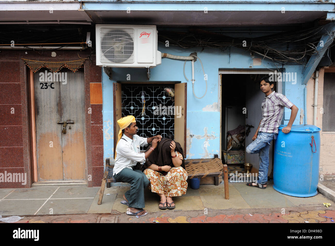 ear cleaner vendor hawker cleaning womans ears in slums of Bachuwadi