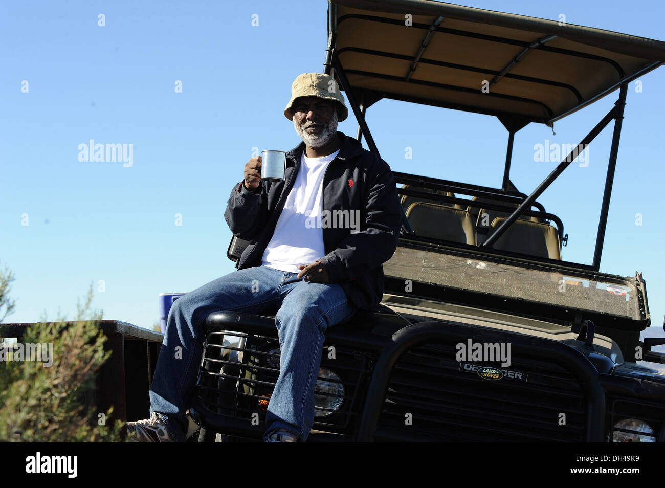 man in hat with coffee mug sitting on safari ride cart south africa   model released Stock Photo