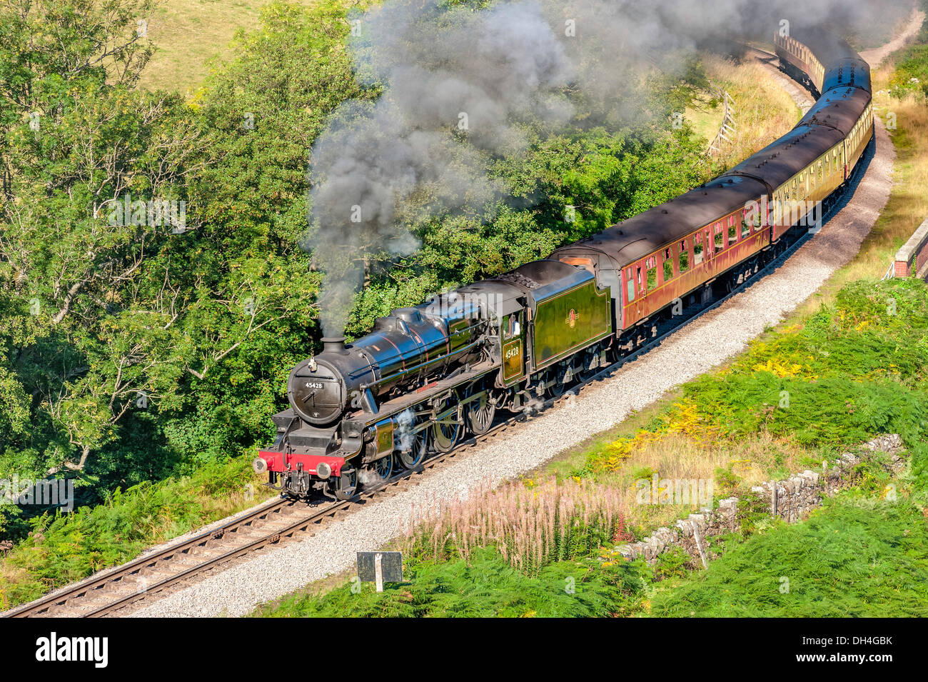 Vintage steam train makes its way through the North York Moors on a bright sunny morning near Goathland, Yorkshire, UK. Stock Photo