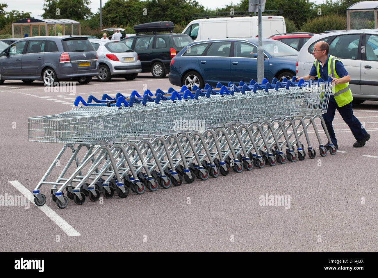 Shopping Trolleys, 23, having been emptied by customers, now being returned to borrowing bays by staff member. Stock Photo