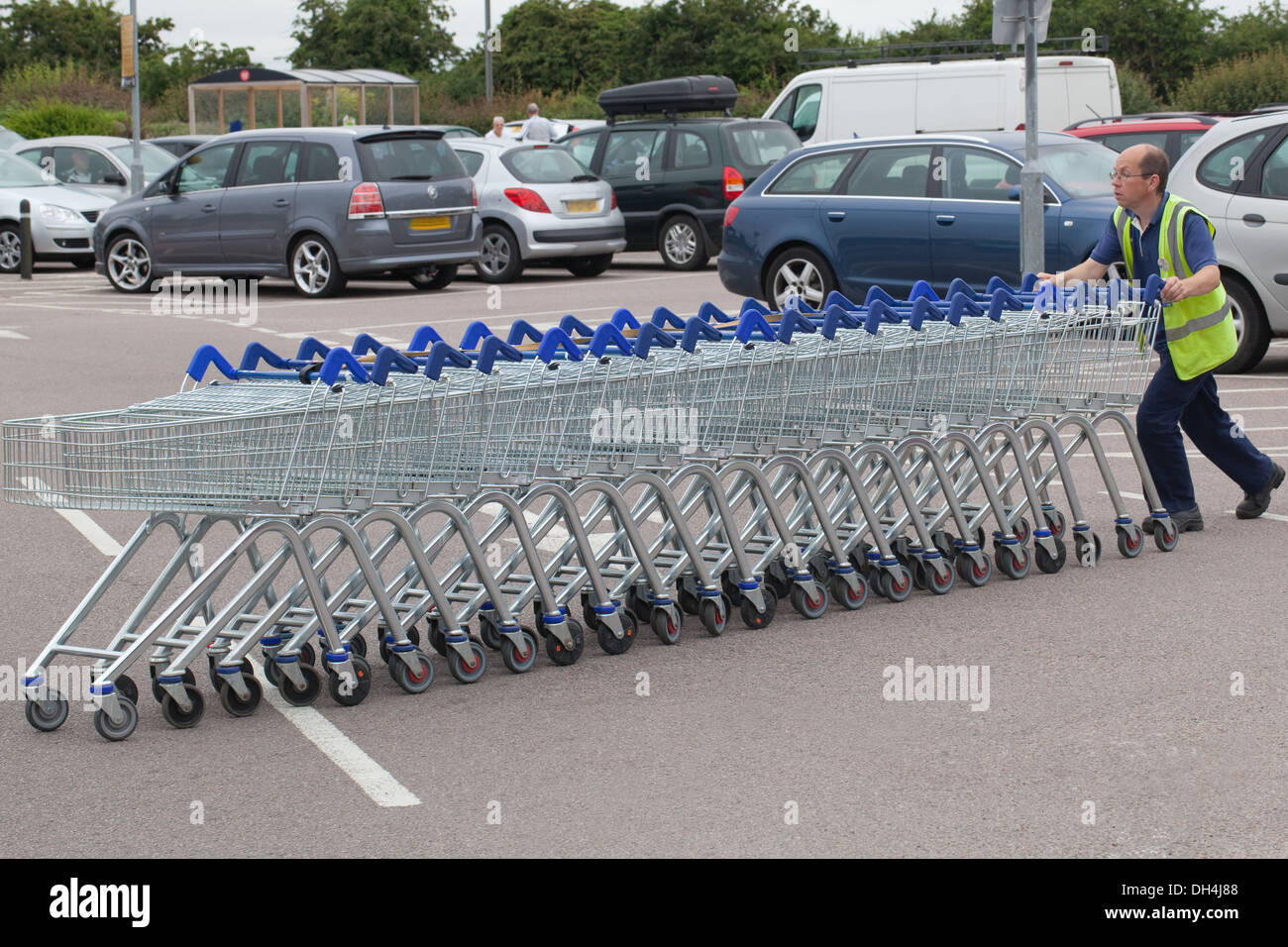 Supermarket Shopping Trolleys, having been emptied by customers, now being returned to borrowing bays by a staff member. Stock Photo