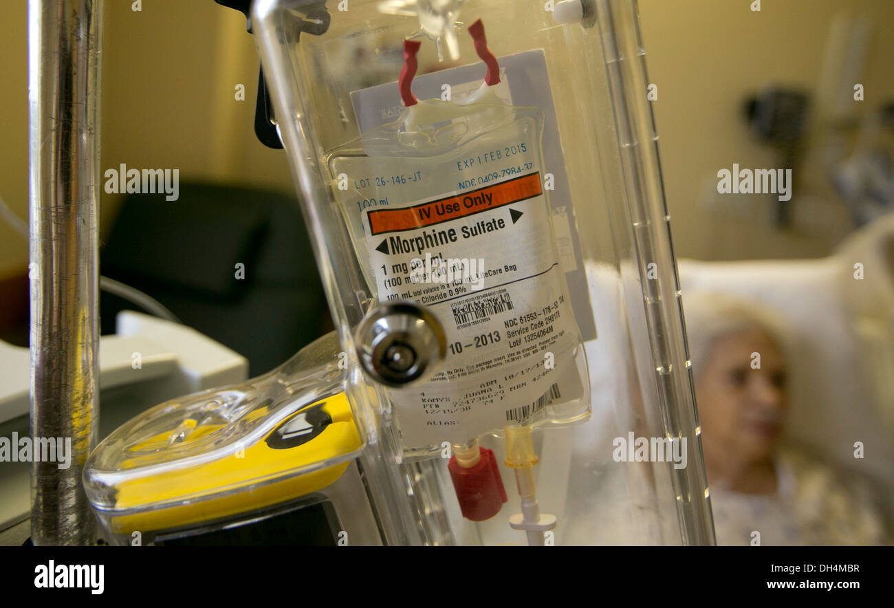 74 year old Hispanic senior woman lays in hospital bed with IV fluids and a morphine drip locked in a plastic box Stock Photo