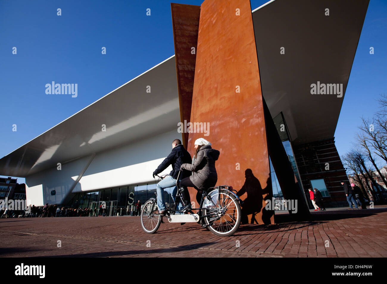 Netherlands, Amsterdam, New annex of the Stedelijk Museum popularly called The Bathtub. Couple on tandem bicycle Stock Photo