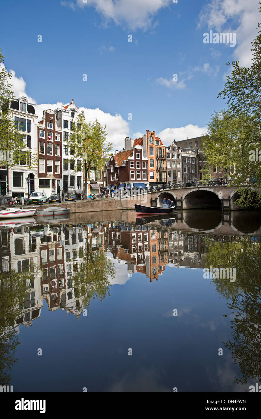 The Netherlands, Amsterdam, Reflection of Canalside houses, houseboats at canal  Singel. Small boat. Unesco World Heritage Site Stock Photo