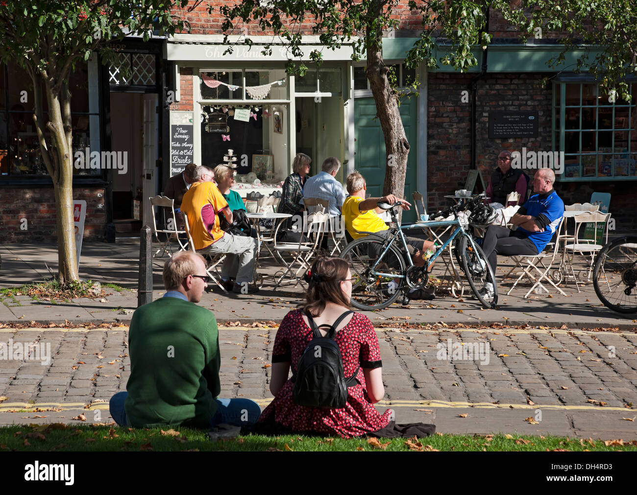 Visitors people tourists relaxing in the autumn sunshine outside cafe in the town city centre York North Yorkshire England UK United Kingdom Britain Stock Photo