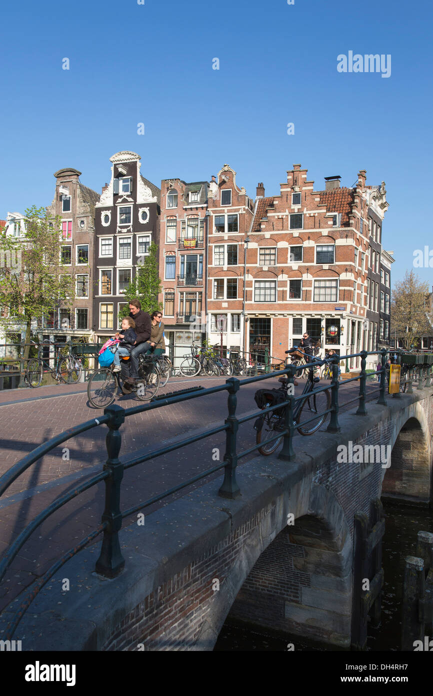 Netherlands, Amsterdam, 17th century houses, canal Brouwersgracht. Cyclists. Father brings children to school on his bike. Stock Photo
