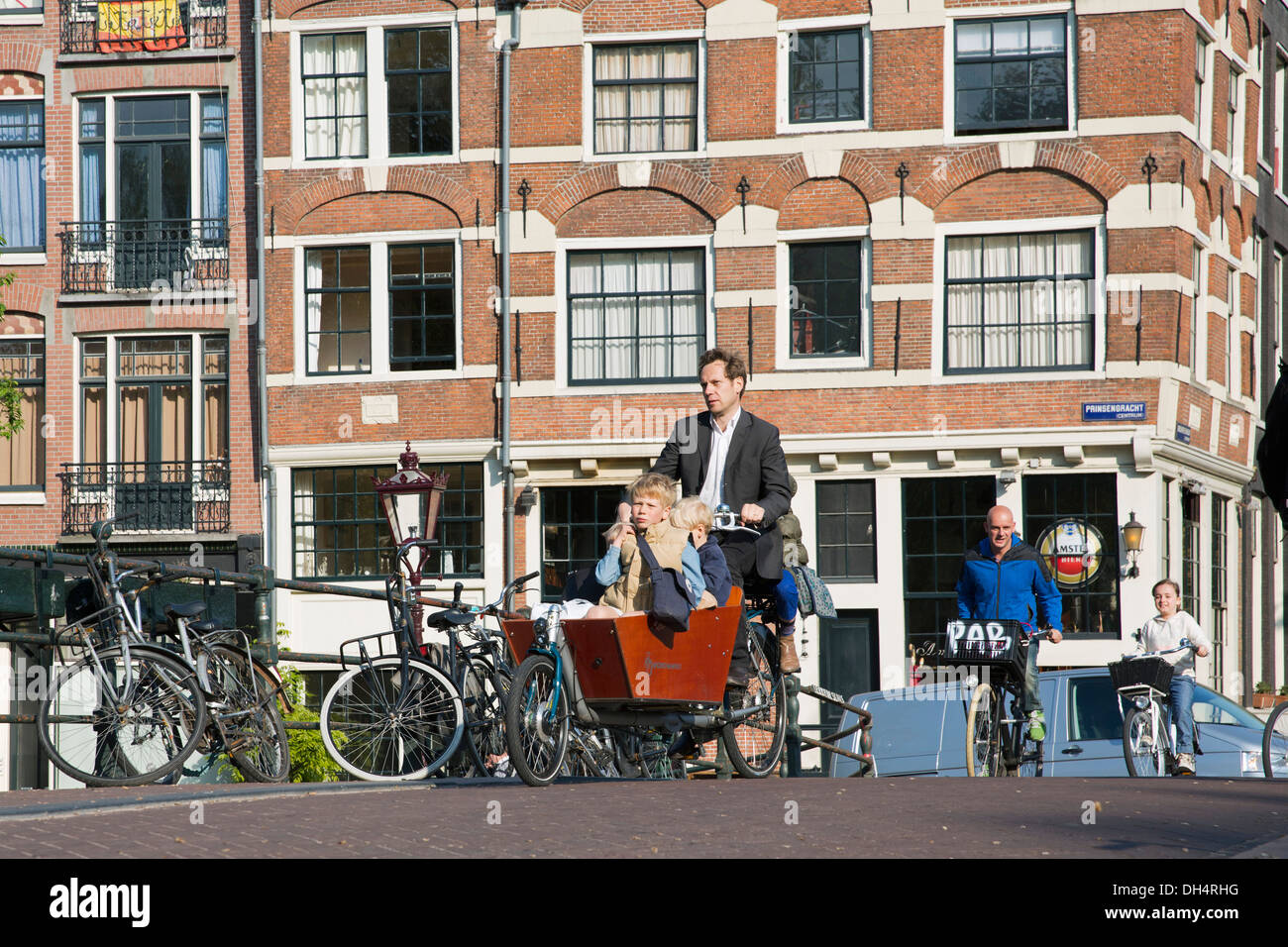 Netherlands, Amsterdam, 17th century houses, canal Brouwersgracht. Cyclists. Father brings children to school on his bike. Stock Photo