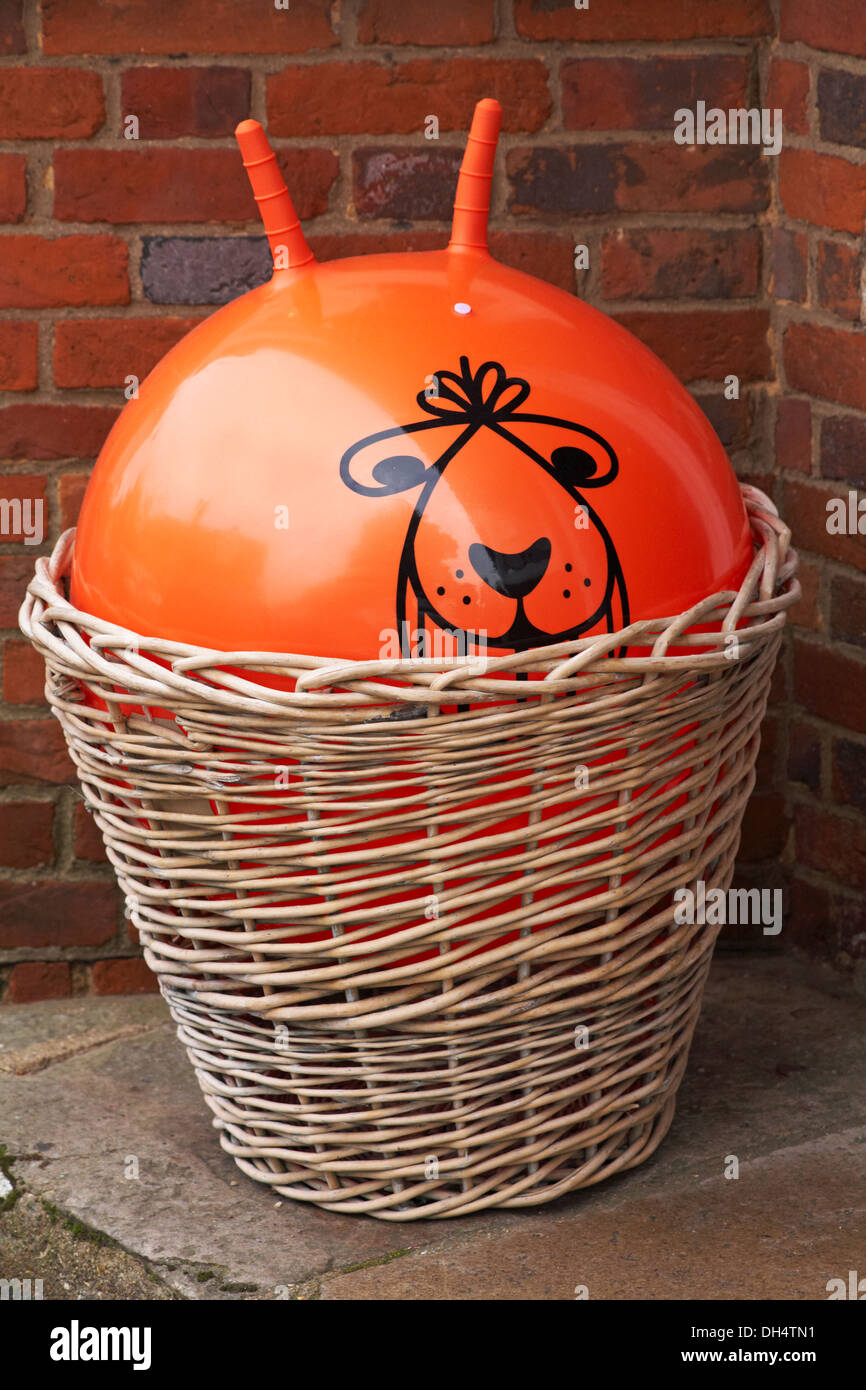 Orange coloured space hopper in basket outside shop in Beaulieu Stock Photo