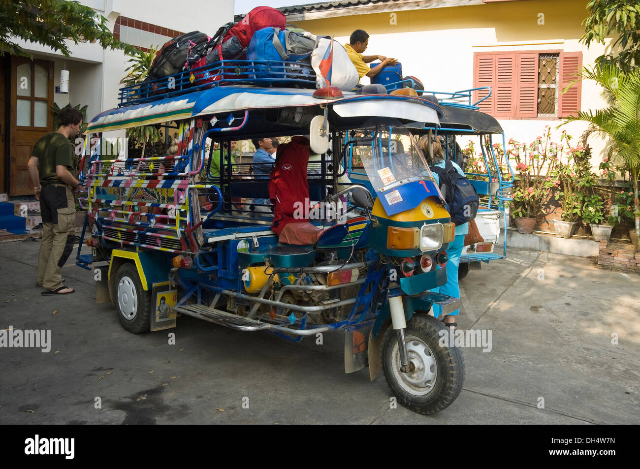Horizontal close up of a jumbo tuk-tuk being loaded with rucksacks on the roof in Luang Prabang. Stock Photo