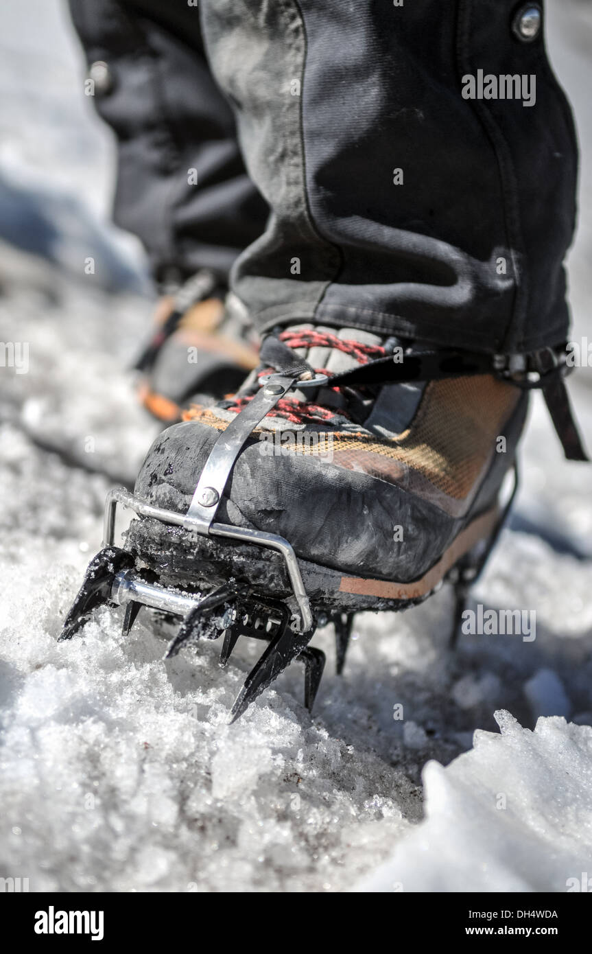A boot with crampons crunches through the ice on a glacier Stock Photo