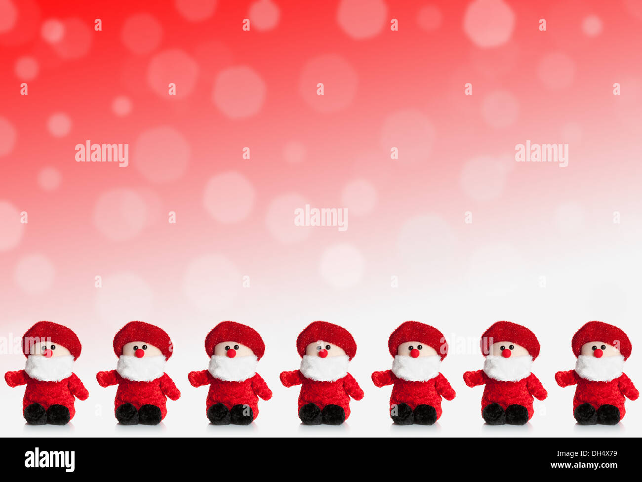 Row of puppets of Santa Claus on a red background with snow. Stock Photo