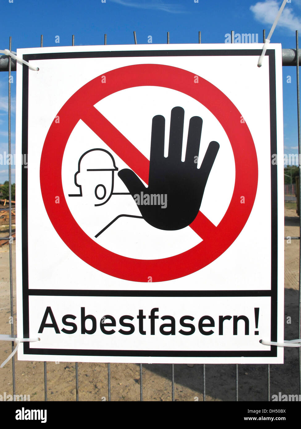 Sign on a fence warning of asbestos fibers Stock Photo