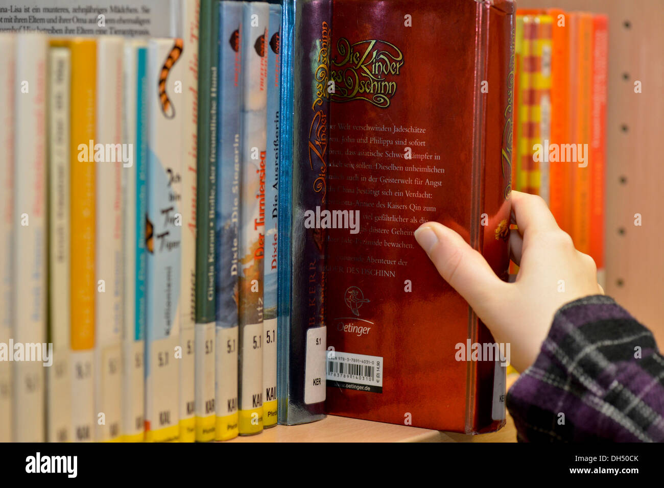 Hand pulling a book from a library shelf Stock Photo