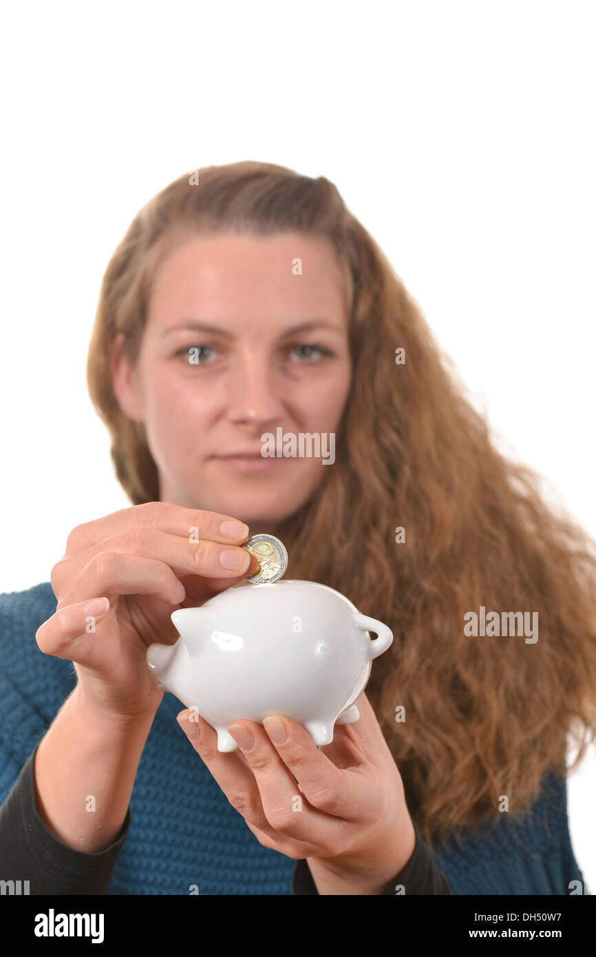 Woman putting a 2 euro coin in a piggy bank Stock Photo - Alamy