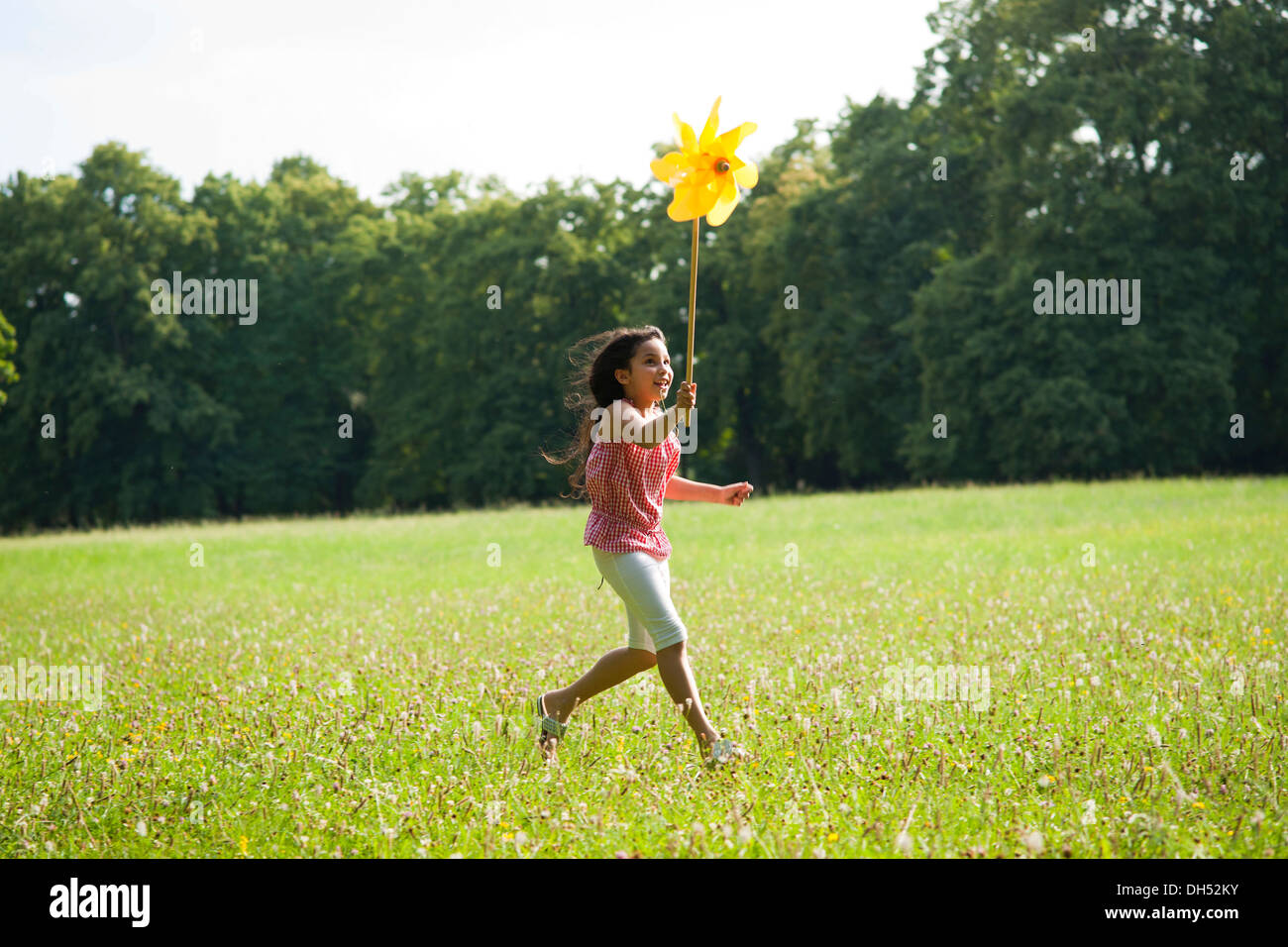 Girl running with a pinwheel on a meadow Stock Photo - Alamy