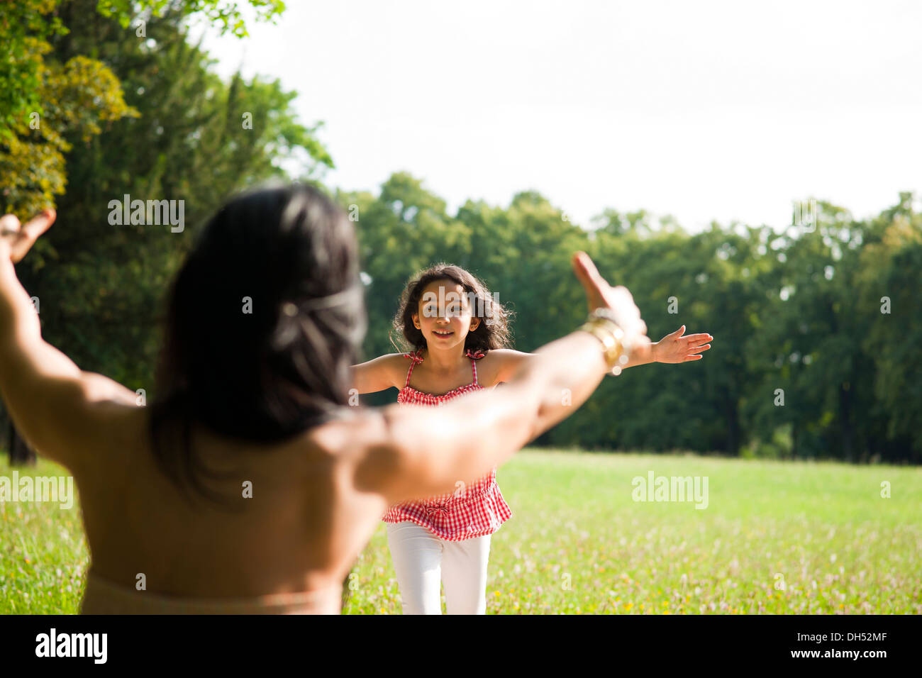 Girl running towards her mother with outstretched arms Stock Photo