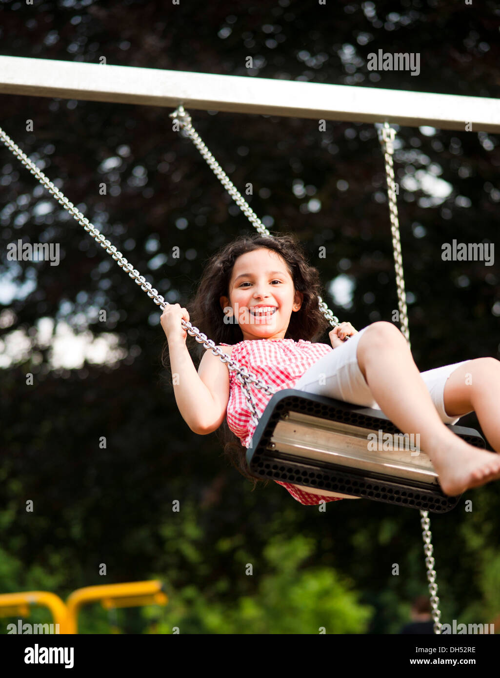 Smiling girl sitting on a swing Stock Photo - Alamy