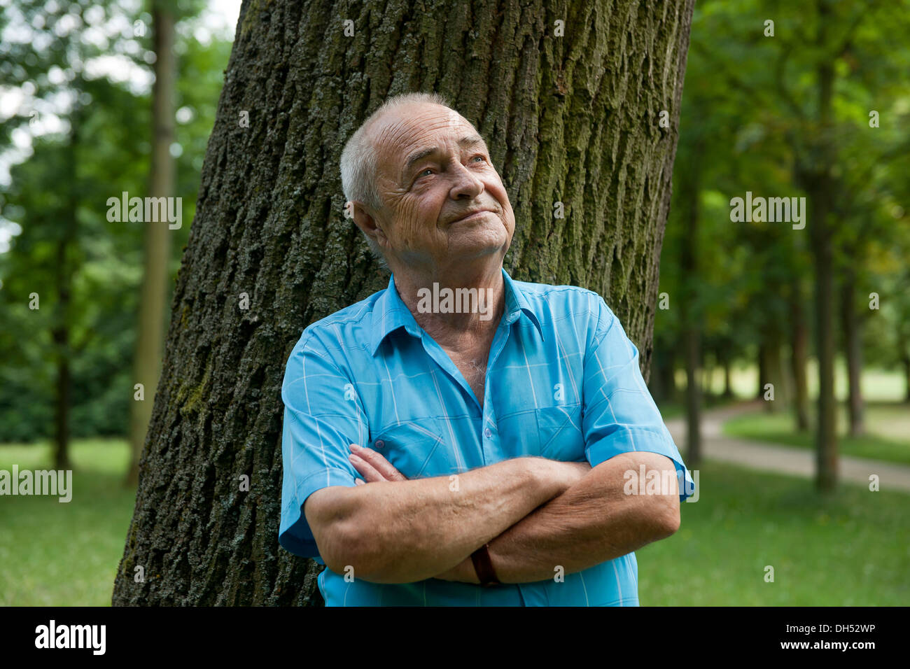 Elderly man leaning against a tree, in a good mood Stock Photo