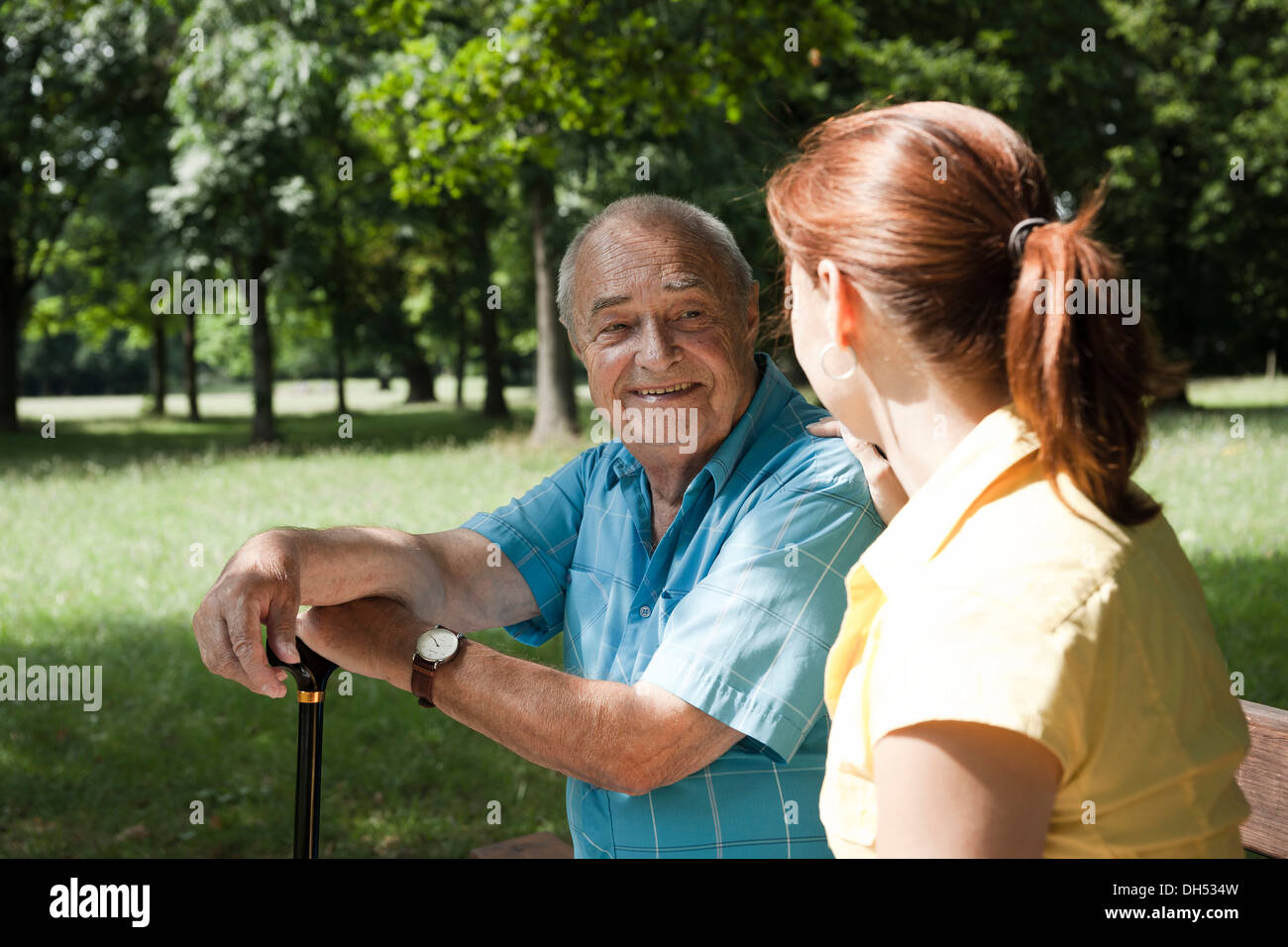 A women and an elderly man having a chat in a park Stock Photo