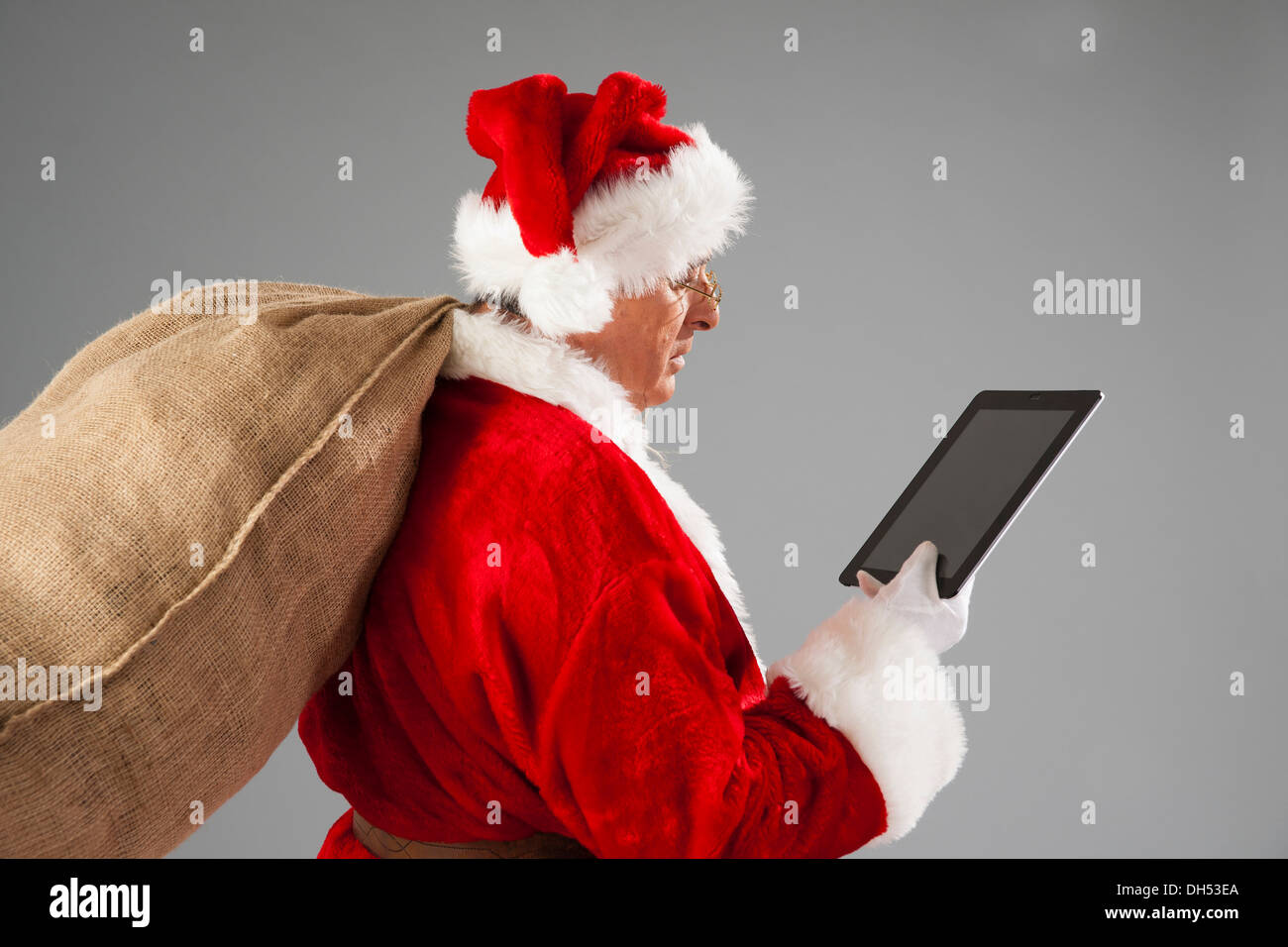 Santa Claus holding a sack and a tablet PC Stock Photo - Alamy
