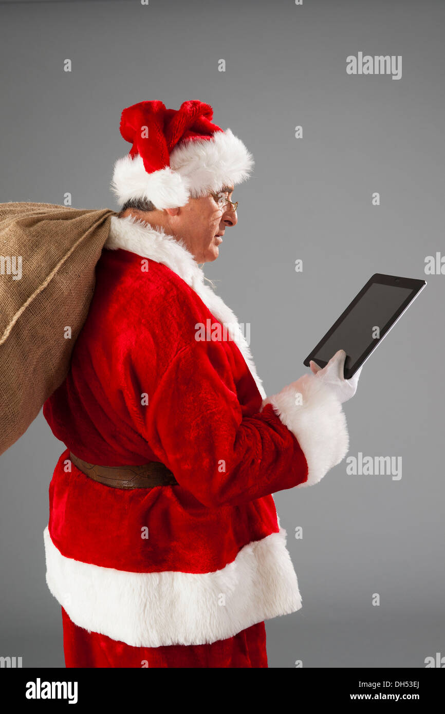 Santa Claus holding a sack and a tablet PC Stock Photo - Alamy
