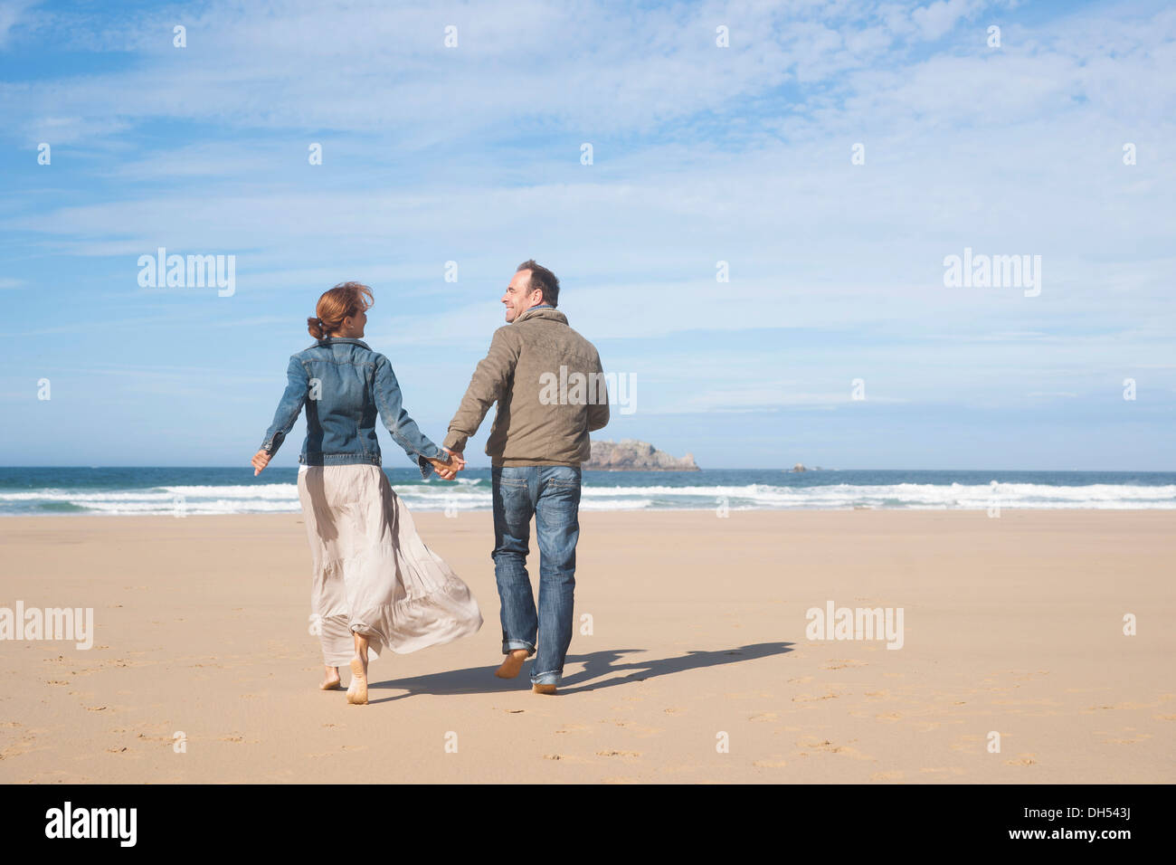 Couple walking along the beach Stock Photo - Alamy