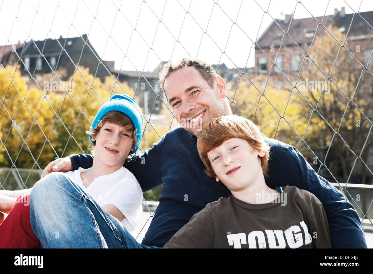 Two cool boys sitting with their father on a playground Stock Photo