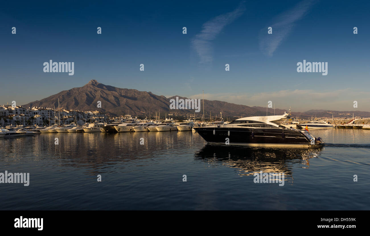 PUERTO BANUS COSTA DEL SOL IN THE EVENING WITH A BLACK BOAT ENTERING THE HARBOUR Stock Photo