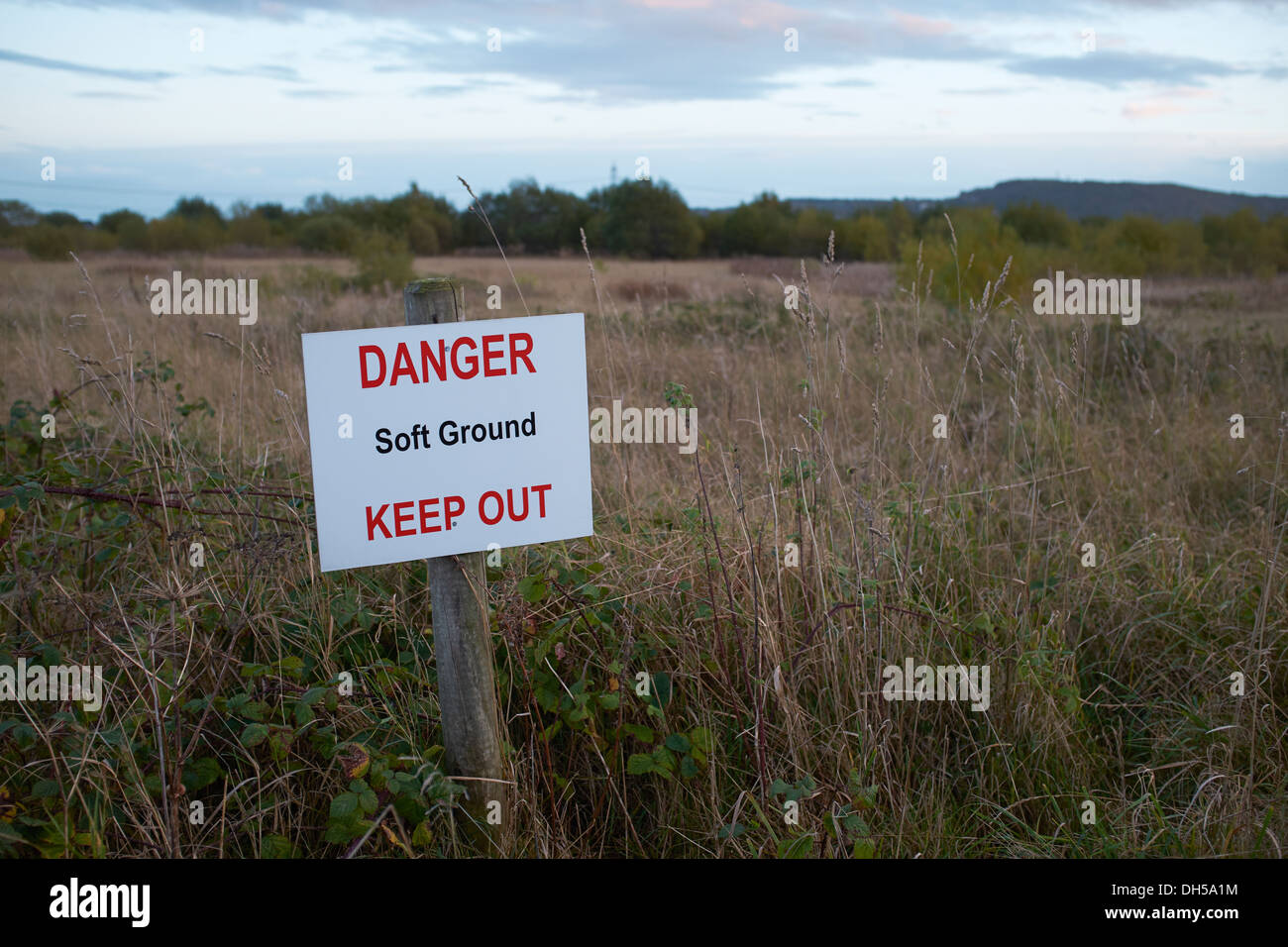 Danger Soft Ground Keep Out sign alongside an area of overgrown land Stock Photo
