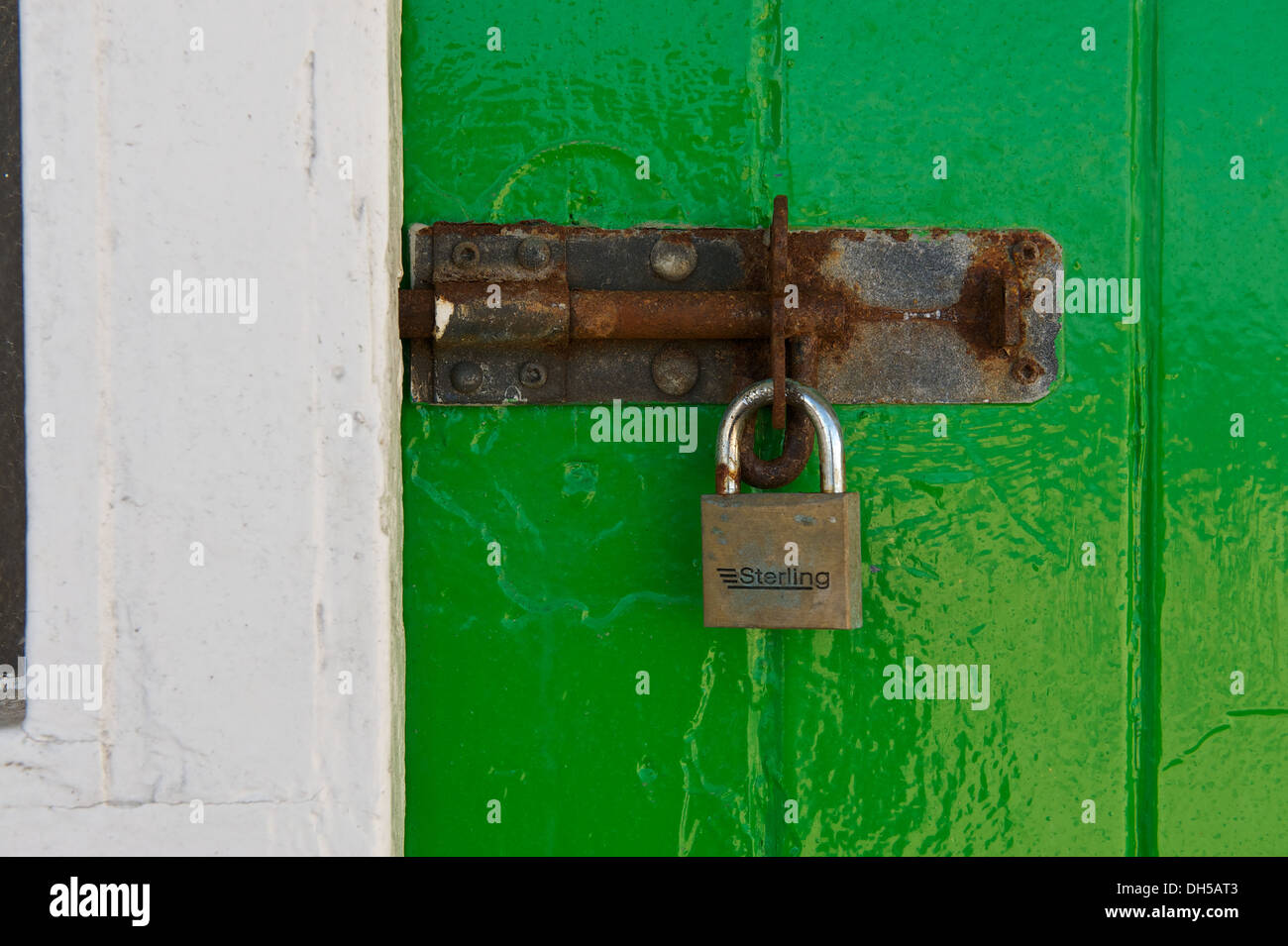 Rusty lock and padlock on a bright green door Stock Photo
