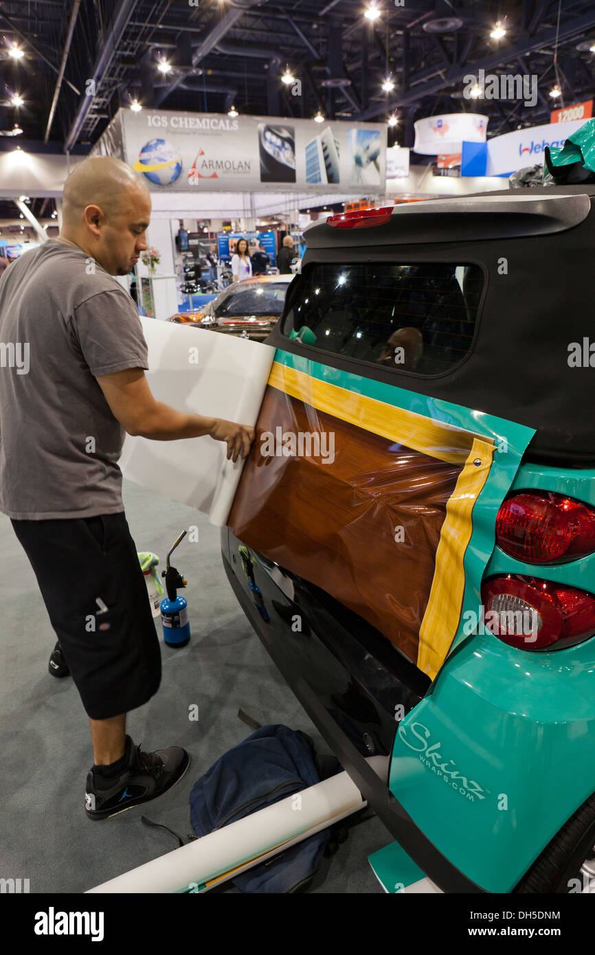 Technician installing vinyl car wrap on SmartCar Stock Photo