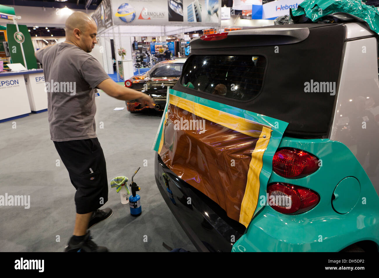 Technician installing vinyl car wrap on SmartCar Stock Photo