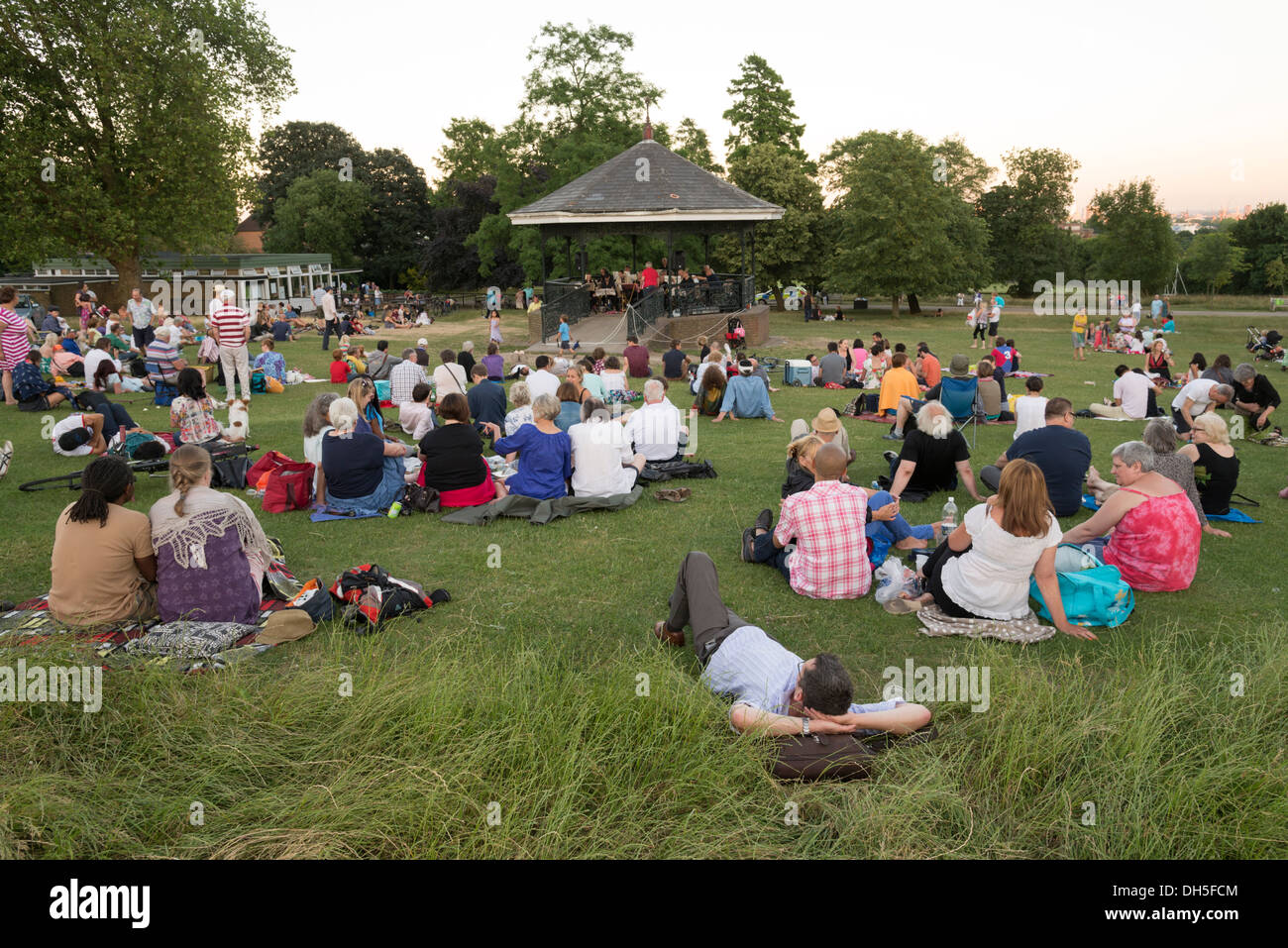 People listening to live music at the Parliament Hill bandstand in Hampstead Heath on a summer evening, London, England, UK Stock Photo