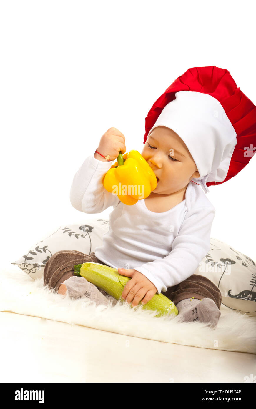 Chef baby boy eating bell pepper and sitting down Stock Photo