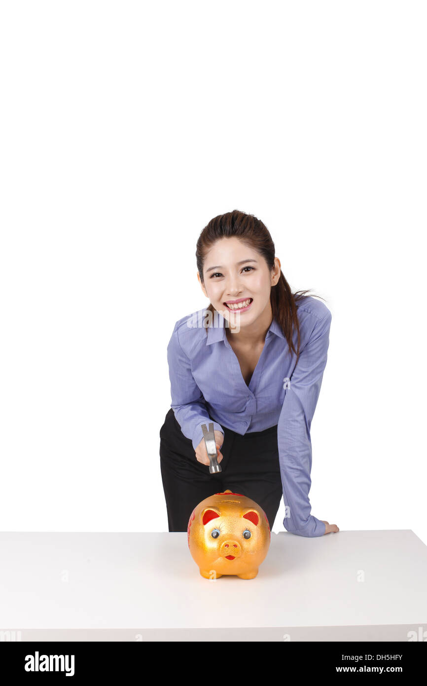 Businesswoman using hammer to smash open a piggy bank Stock Photo - Alamy