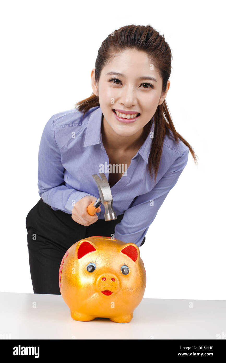 Businesswoman using hammer to smash open a piggy bank Stock Photo - Alamy