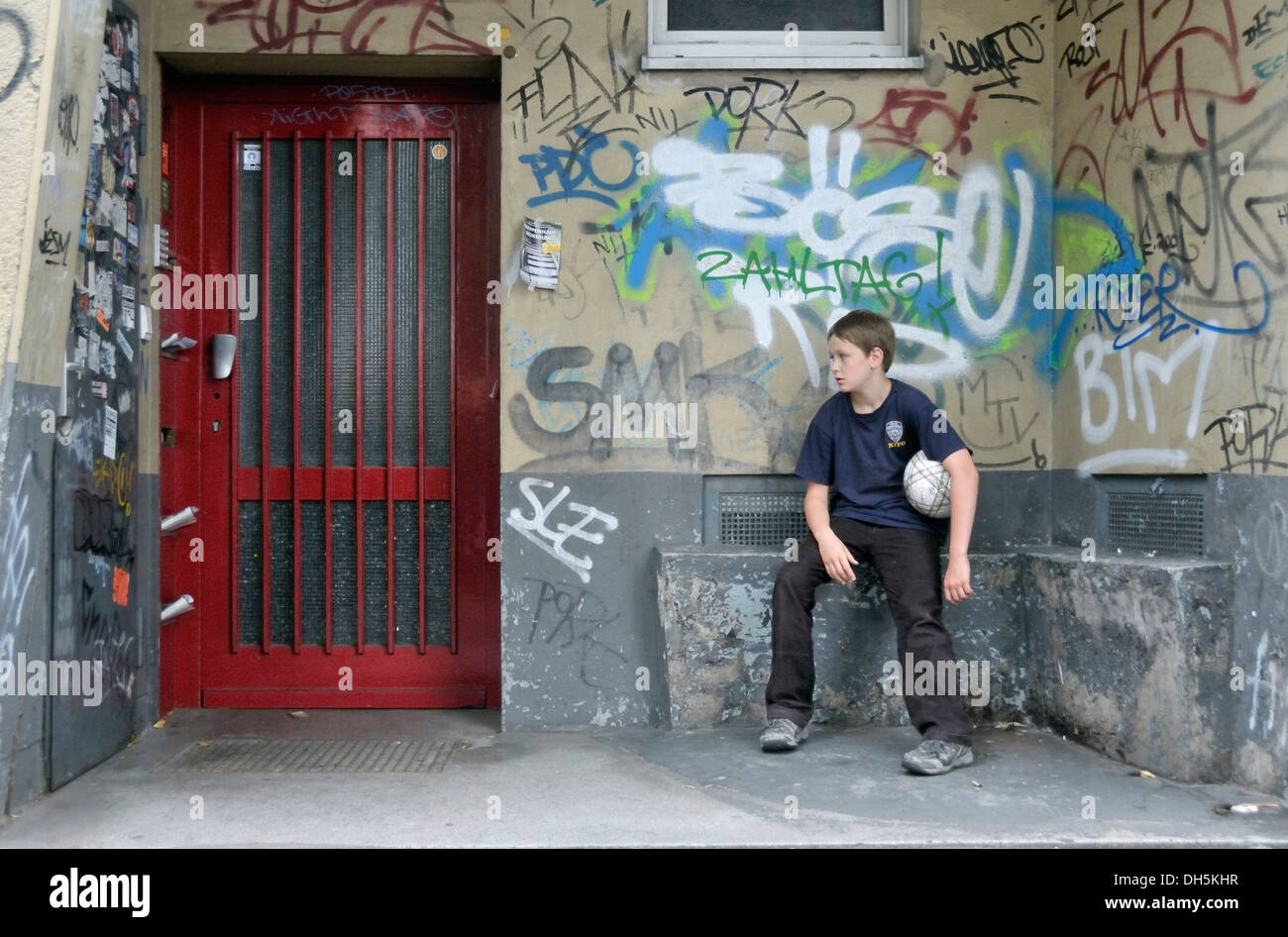 Weary boy, 10 years, sitting in a doorway, Cologne, North Rhine-Westphalia Stock Photo