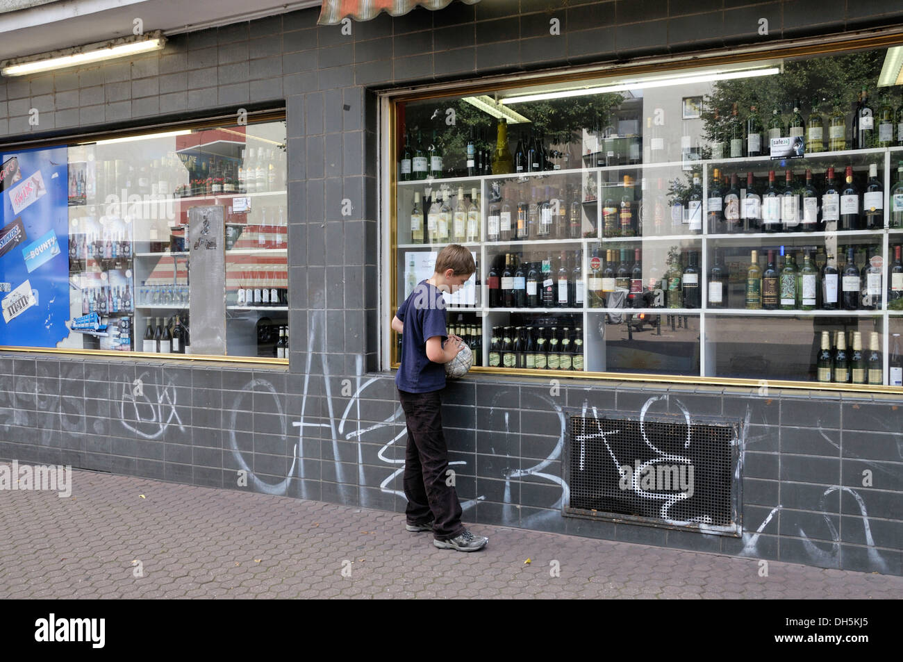 Boy, 10 years, looking at alcoholic beverages in the window of a drinks market, Cologne, North Rhine-Westphalia Stock Photo