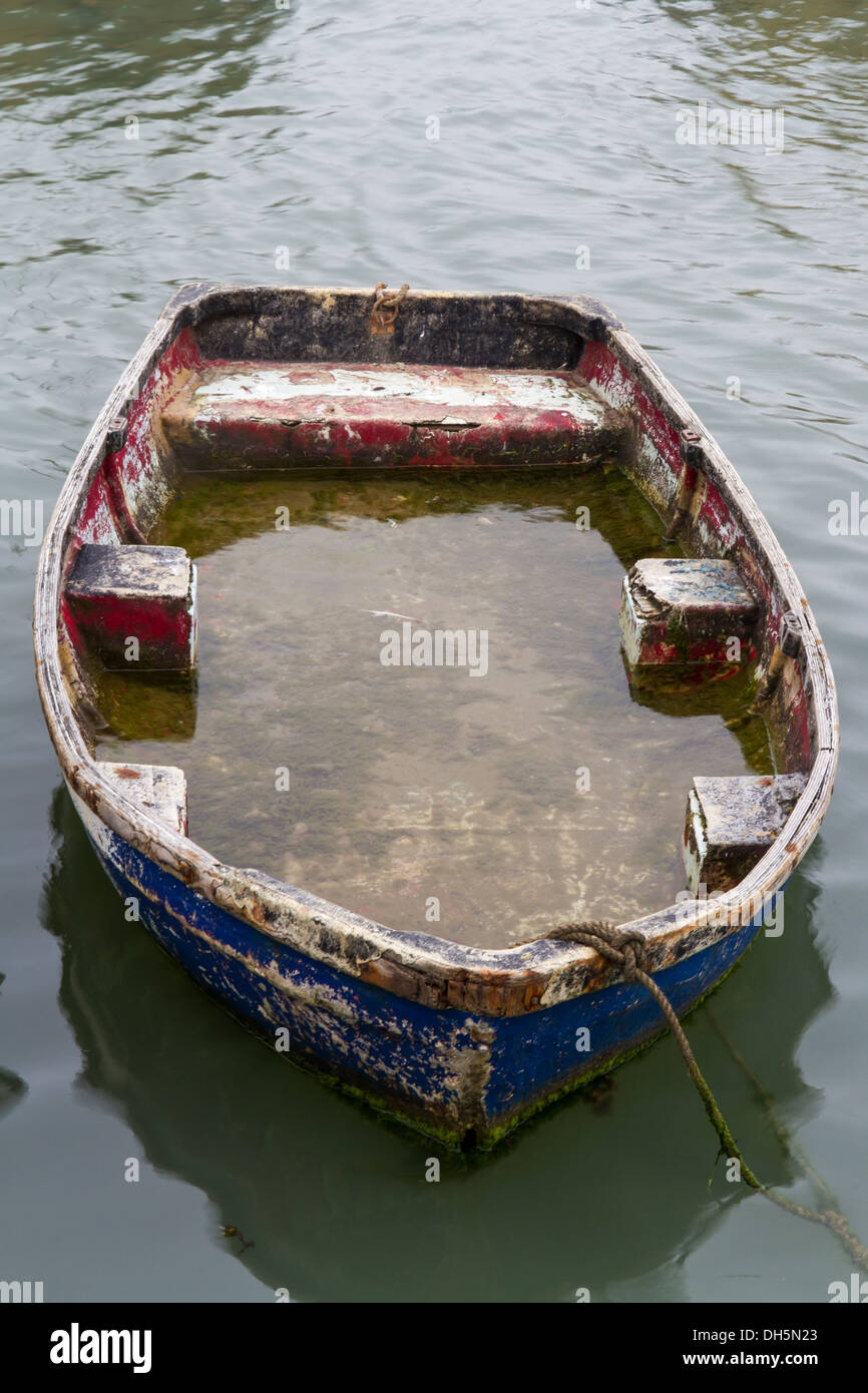 Small rowing boat half filled with water. Stock Photo