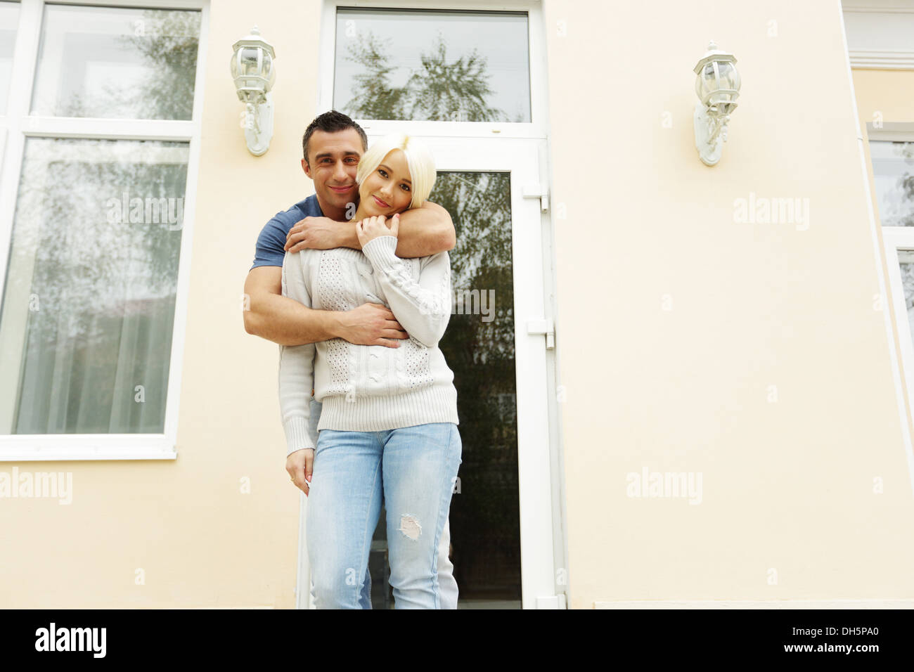 Happy couple standing in front of their new house Stock Photo - Alamy