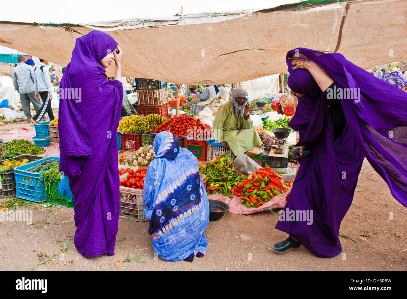 Three Berber women in front of a greengrocer's stall in the souks or bazaar area, Draa Vally, southern Morocco, Morocco, Africa Stock Photo